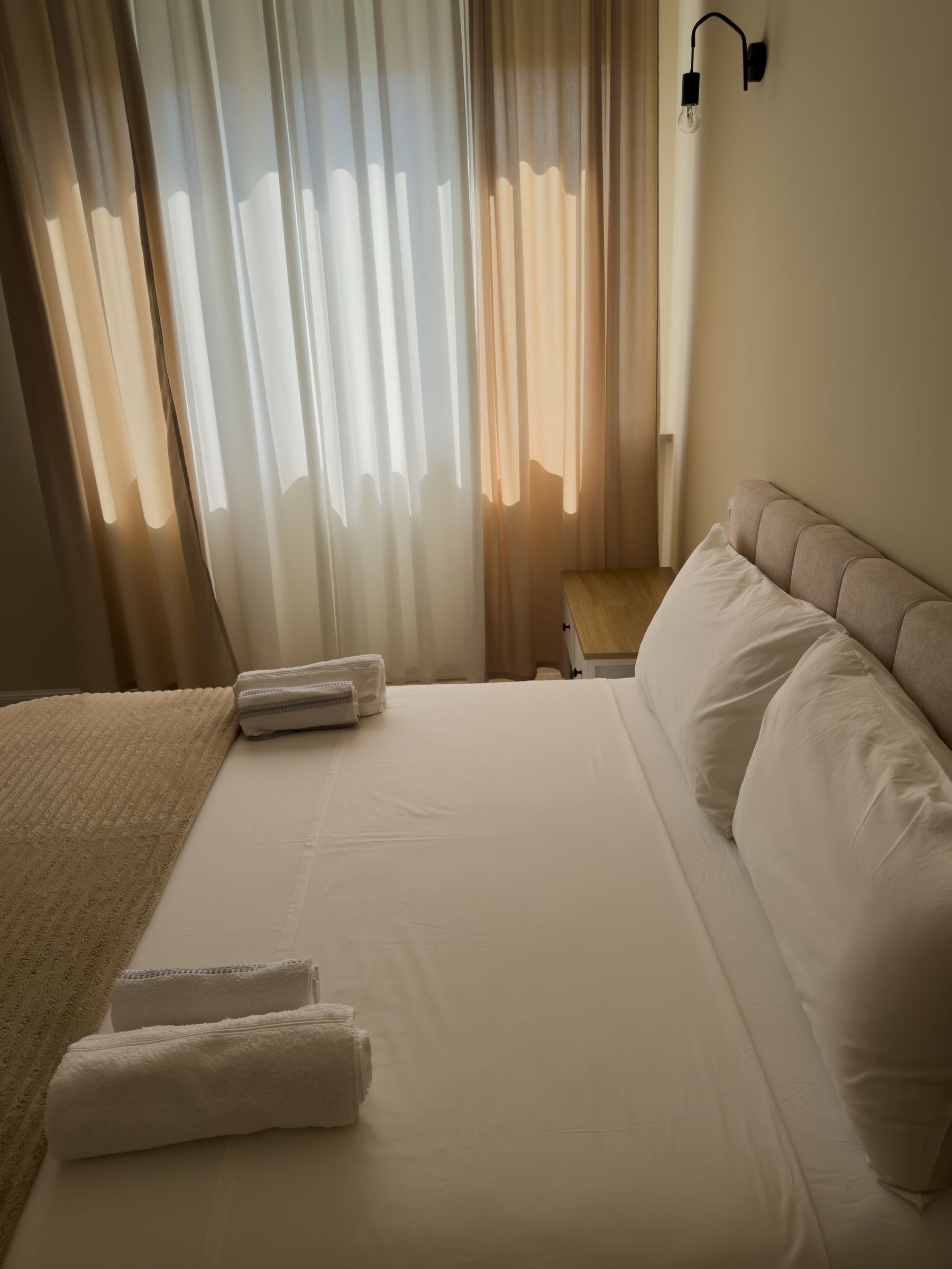 Letto rifatto di fresco con la luce del pomeriggio che entra dalle tende
